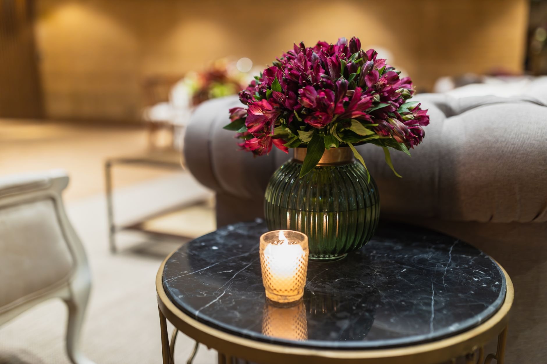 Cosy living space with a vibrant flower arrangement and a lit candle creating warm ambiance