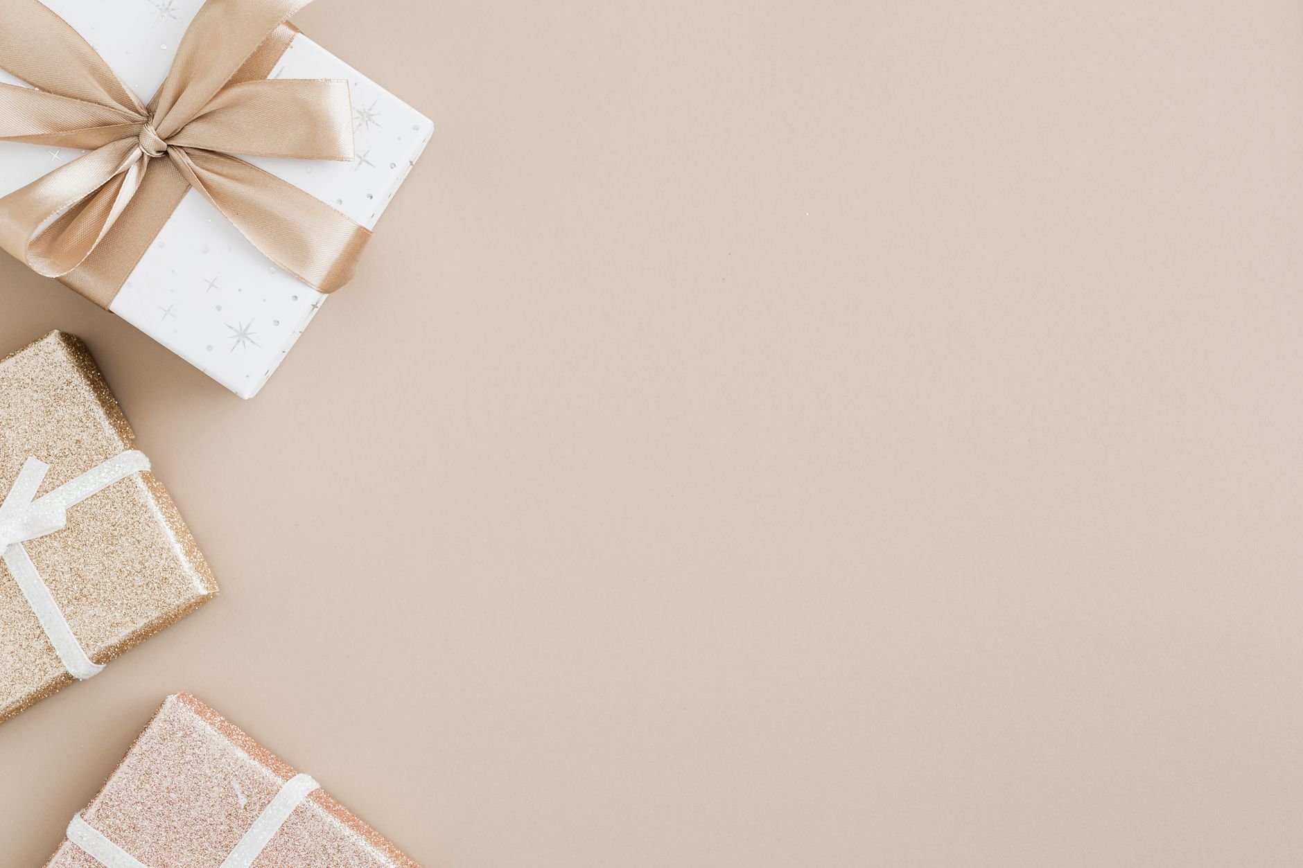 High-angle view of gift boxes with ribbons on a beige background, elegant and minimal style