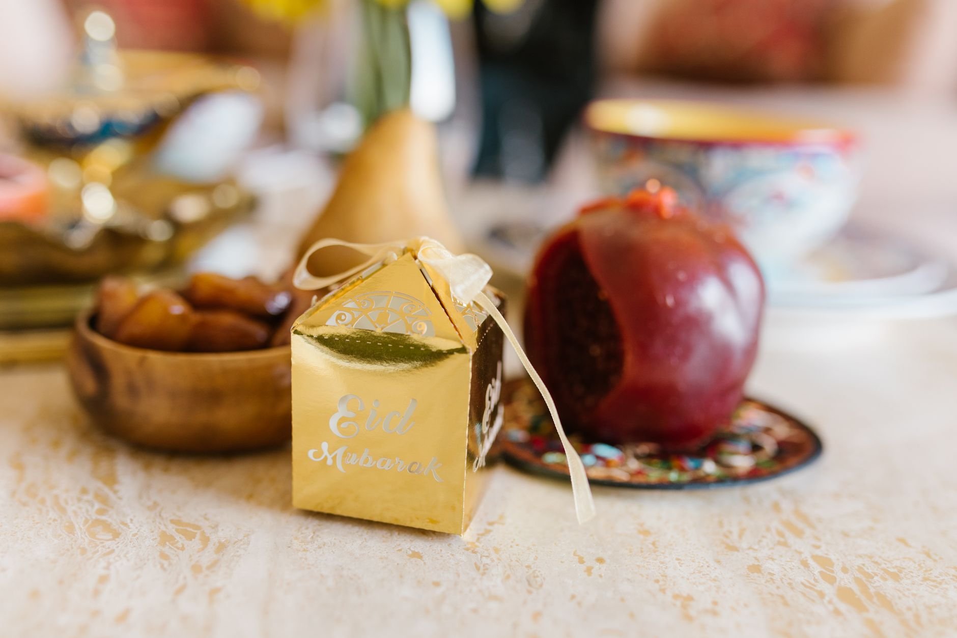 Warm Eid table setting with a decorative gift box, pomegranate, and traditional dishes